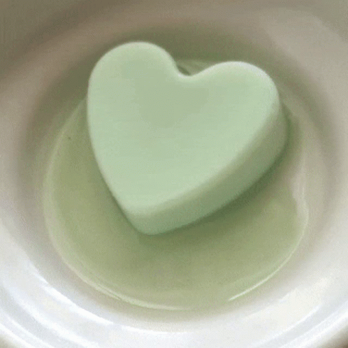 A Green Heart Shaped Soap Is In A White Bowl GIF