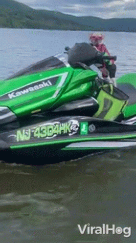 A Green Kawasaki Jet Ski Is Floating On The Water GIF