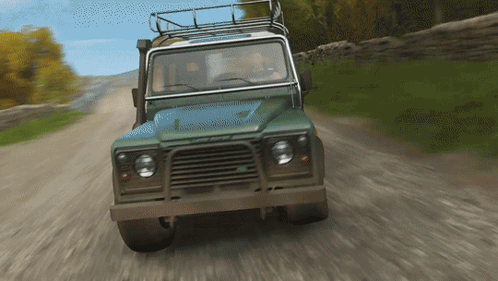 A Green Land Rover Is Driving Down A Dirt Road With Trees In The Background GIF