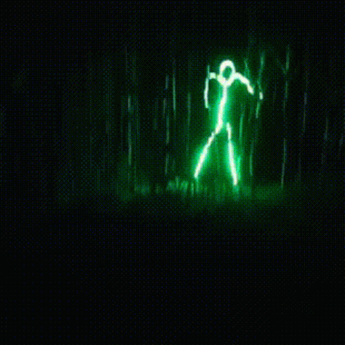 A Green Light That Looks Like A Person Standing In A Forest GIF