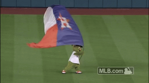 A Green Mascot Is Holding A Texas Flag GIF
