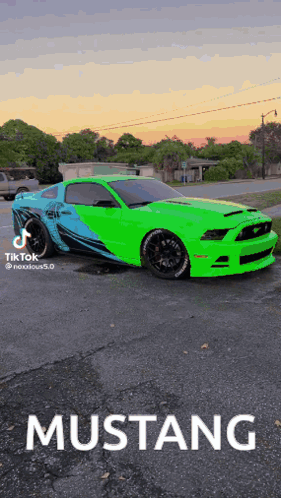 a green mustang is parked in a parking lot at sunset