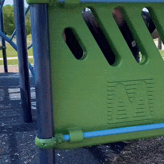 a green playground with a blue railing and a green fence with the letter m on it