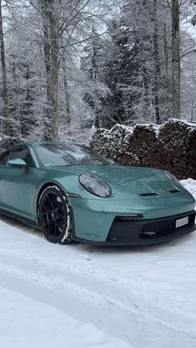 A Green Porsche 911 Gt3 Is Parked In The Snow . GIF