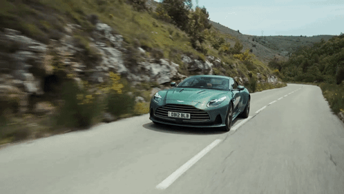 A Green Sports Car Is Driving Down A Road With A License Plate That Says Rb12 Ln GIF