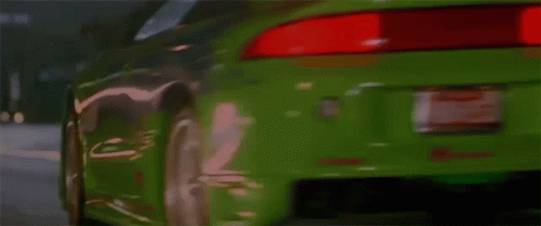 A Green Sports Car Is Driving Down A Street And Has The Word Turbo On The Hood GIF