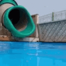 A Green Tube Is Going Down A Water Slide Into A Pool GIF
