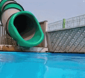 A Green Water Slide Is Going Down A Pool GIF