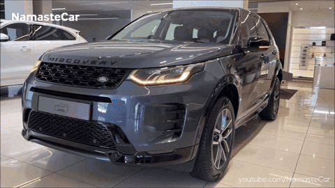 A Grey Land Rover Discovery Is Shown In A Showroom GIF
