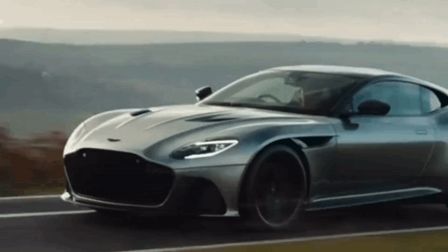 A Grey Sports Car Is Driving Down A Road GIF