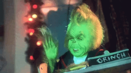 A Grinch Is Sitting In A Chair And Waving GIF