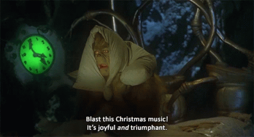 A Grinch Says Blast This Christmas Music It 'S Joyful And Triumphant In Front Of A Clock GIF