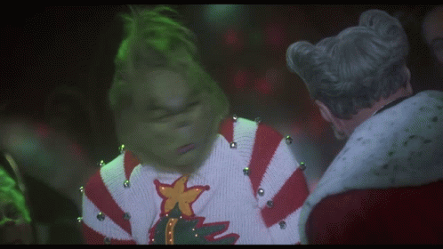 A Grinch Wearing A Sweater With A Star On It GIF
