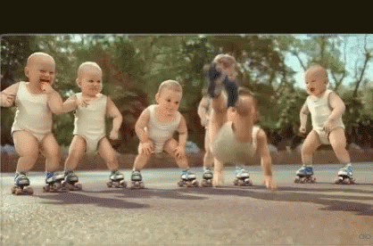 A Group Of Babies Are Rollerblading On A Road . GIF