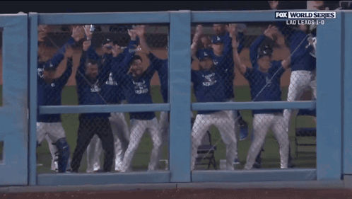 A Group Of Baseball Players Are Behind A Fence With Fox World Series Written Above Them GIF