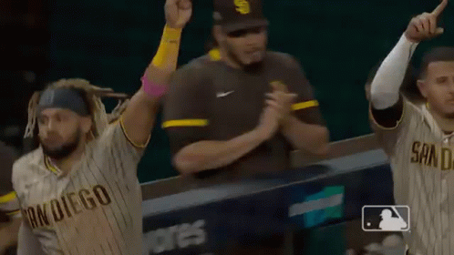 A Group Of Baseball Players Are Celebrating A Win While A Referee Watches . GIF