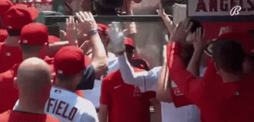 A Group Of Baseball Players Are Giving Each Other A High Five While Standing In A Dugout . GIF