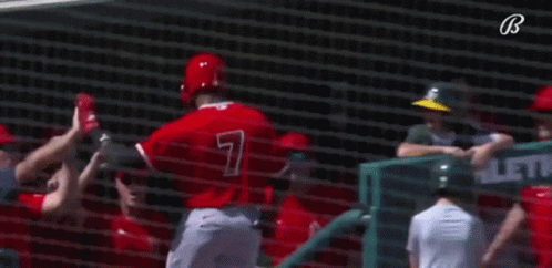 A Group Of Baseball Players Are Giving Each Other A High Five While Standing In Front Of A Net . GIF