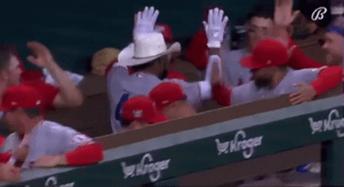 A Group Of Baseball Players Are Sitting In A Dugout . GIF