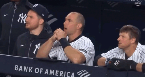 A Group Of Baseball Players Are Sitting In A Dugout With A Bank Of America Banner Behind Them GIF