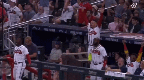 A Group Of Baseball Players Are Standing In A Dugout With A Banner That Says Proud Partner GIF