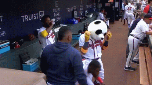 A Group Of Baseball Players Are Standing In A Dugout With A Panda Mascot GIF