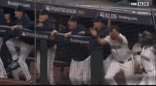 A Group Of Baseball Players Are Standing In A Dugout With A Sign That Says Postseason GIF