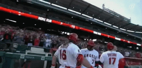 A Group Of Baseball Players Are Standing In A Stadium With A Banner That Says Home Run GIF
