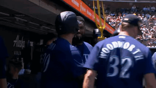 A Group Of Baseball Players Are Standing Next To Each Other In A Dugout . GIF