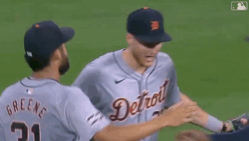 A Group Of Baseball Players Hugging Each Other On The Field GIF