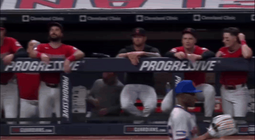 A Group Of Baseball Players Sitting In A Dugout With Progressive Advertisements On The Wall GIF