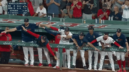 A Group Of Baseball Players Standing Behind A Green Xfinity Sign GIF
