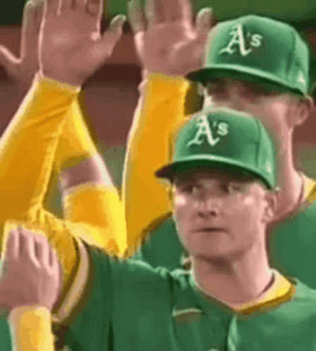 A Group Of Baseball Players Wearing Green And Yellow Uniforms Are Giving Each Other A High Five . GIF