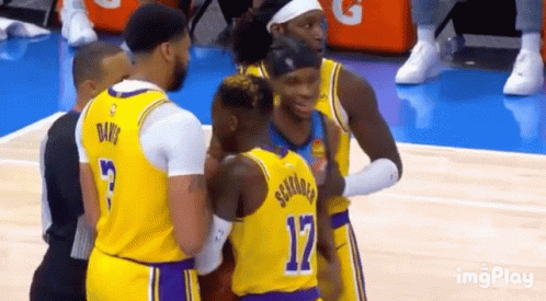 A Group Of Basketball Players Are Hugging Each Other On The Court . GIF