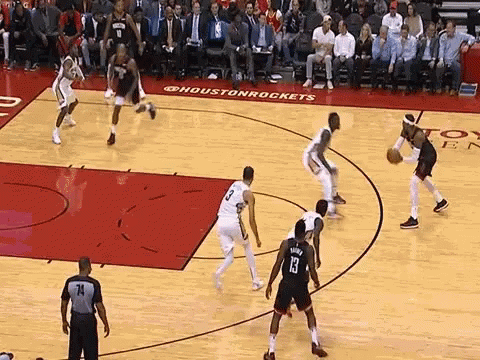 A Group Of Basketball Players Are Playing A Game Of Basketball On A Court With A Referee Watching . GIF