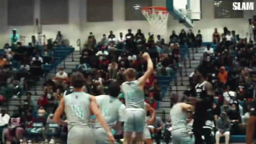 A Group Of Basketball Players Are Playing Basketball In Front Of A Crowd . GIF