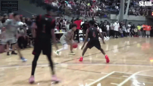 A Group Of Basketball Players Are Playing Basketball On A Court In Front Of A Crowd . GIF