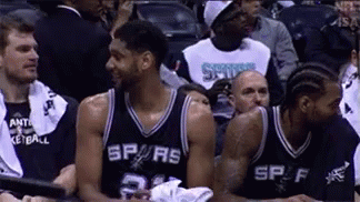 A Group Of Basketball Players Are Sitting In A Stadium . GIF
