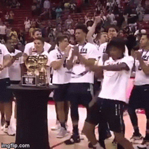 A Group Of Basketball Players Are Standing Around A Trophy With The Number 23 On Their Shirts GIF