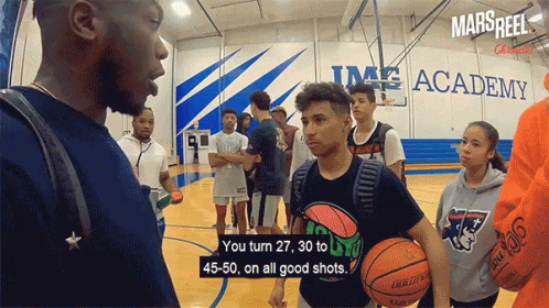 A Group Of Basketball Players Are Standing On A Court In Front Of A Sign That Says Mars Reel GIF