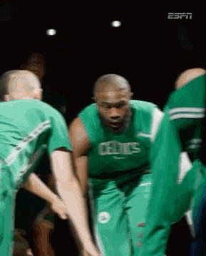 A Group Of Basketball Players Wearing Green Uniforms Are Huddled Together . GIF