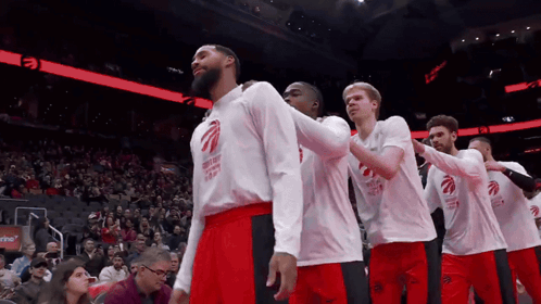 A Group Of Basketball Players Wearing Toronto Raptors Shirts Stand In A Row GIF