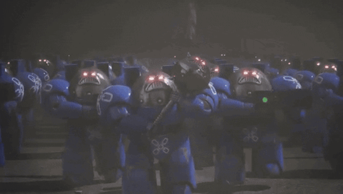 A Group Of Blue Robots With Red Lights On Their Faces Are Standing Next To Each Other . GIF