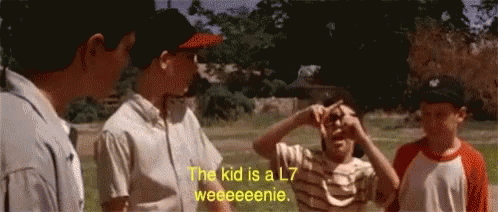 A Group Of Boys Are Standing In A Field With One Saying The Kid Is A L7 Weeeeenie GIF