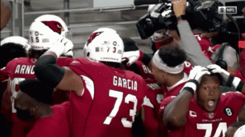 A Group Of Cardinals Football Players Huddled Together GIF