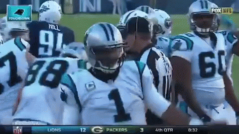 A Group Of Carolina Panthers Football Players Are Huddled Around A Referee GIF
