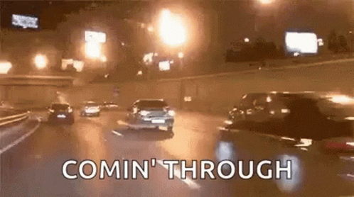 A Group Of Cars Are Driving Down A Highway At Night And The Words Comin ' Through Are Visible . GIF