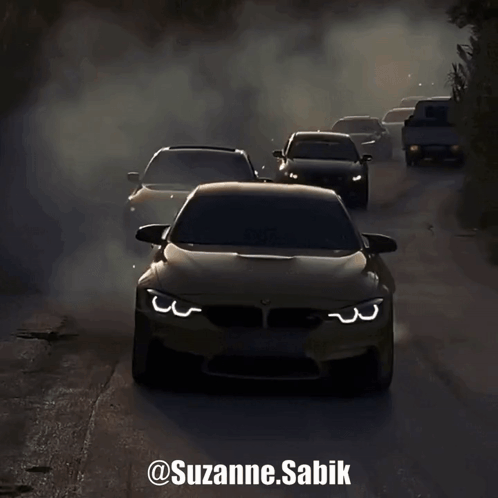 A Group Of Cars Driving Down A Road With Smoke Coming Out Of Their Tires GIF