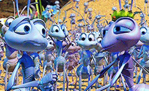A Group Of Cartoon Ants Are Standing In The Sand GIF