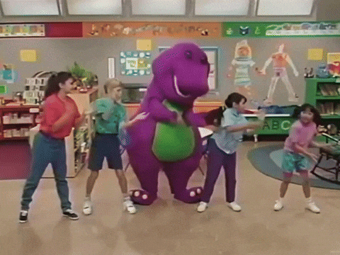 A Group Of Children Are Dancing Around A Purple Dinosaur In A Classroom With A Sign That Says Abc GIF
